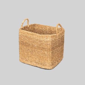 Handwoven square seagrass storage basket with sturdy integrated handles, styled in a modern living room and used for blanket storage. Natural woven basket for home organisation, laundry, toys, books, and decorative storage.